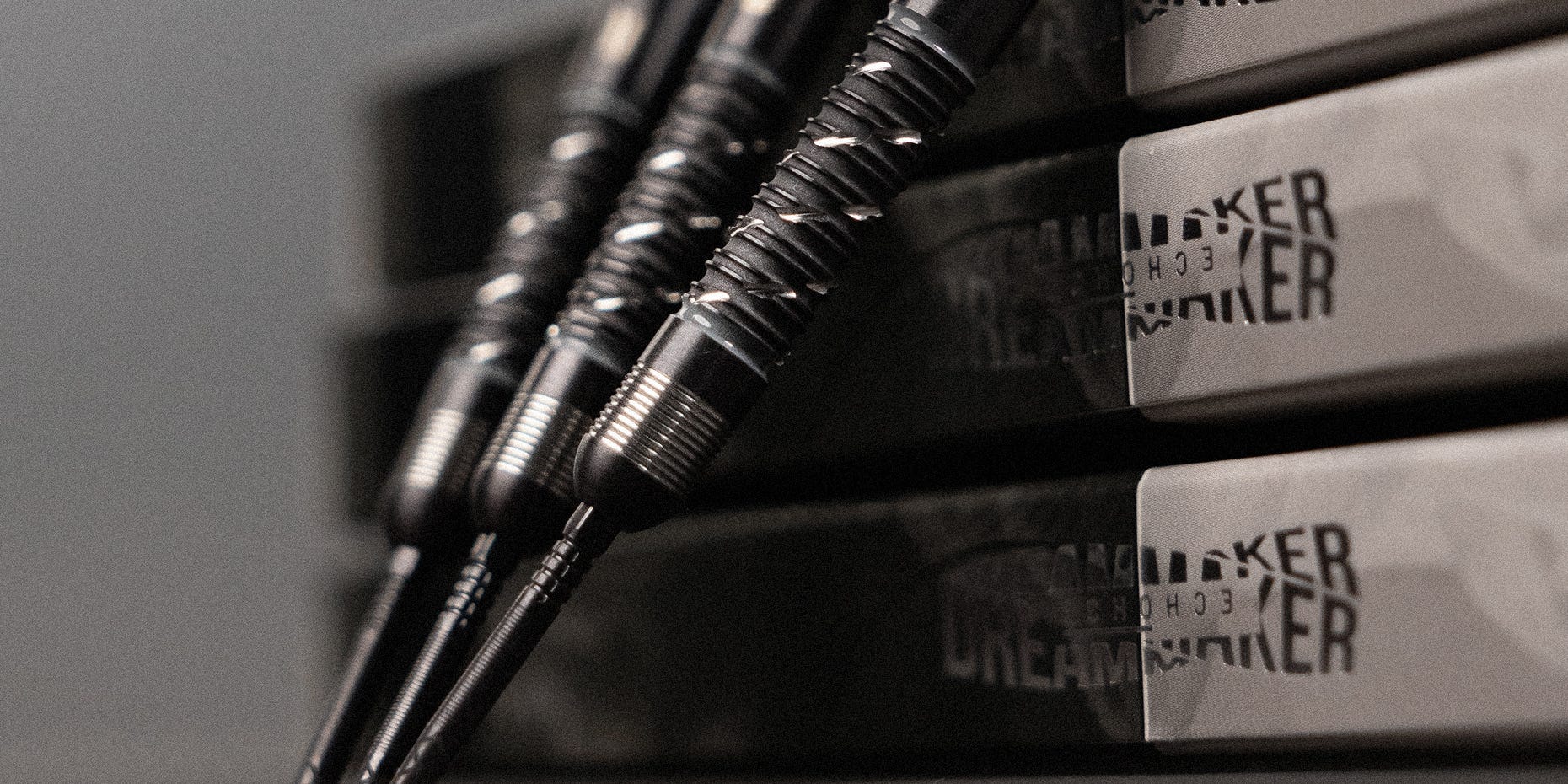 A set of Dimitri Van den Bergh x Echo steel tip darts leaning against the Dimitri Van den Bergh x Echo box.