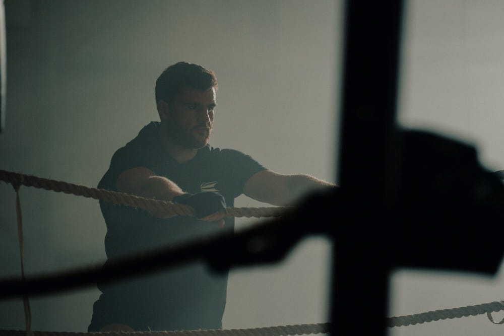 Johnny Fisher next to boxing ring hanging on the ropes