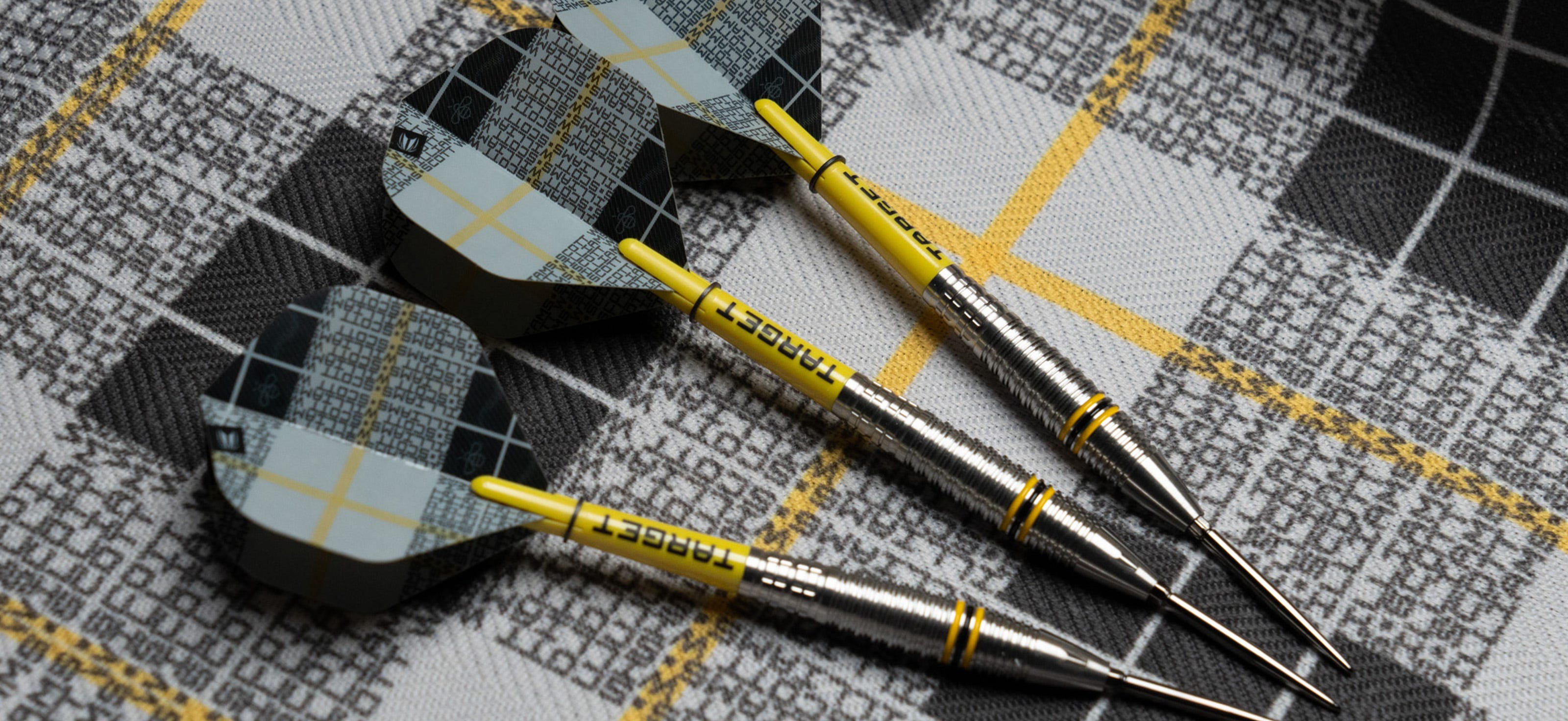 Set of Scott Williams G2 steel tip darts laid on plaid background